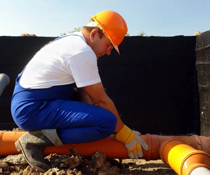 A man in an orange helmet is working on the ground.