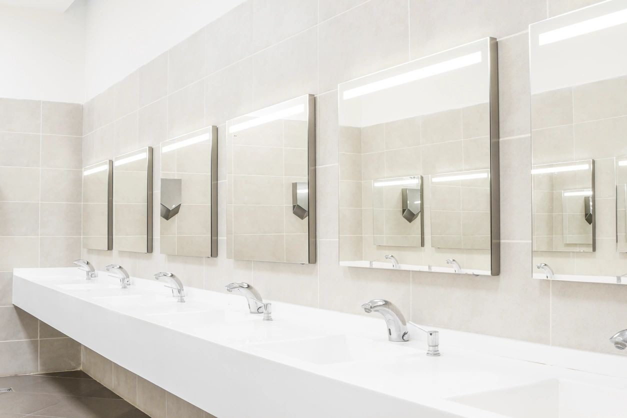 A row of sinks in a bathroom with mirrors.