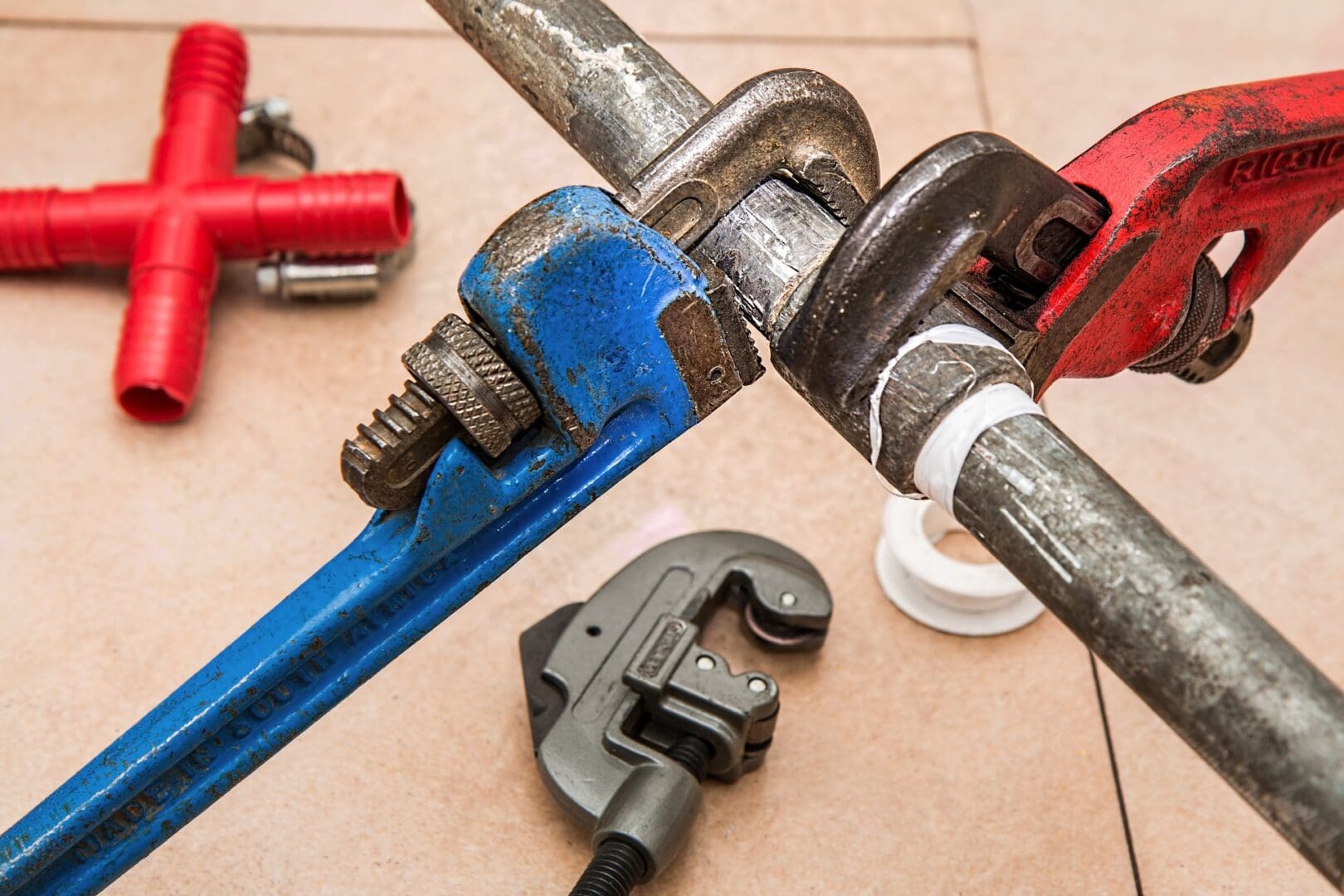 A pipe wrench and other tools are laying on the floor.